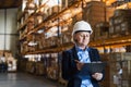 Senior woman warehouse manager or supervisor with white helmet and clipboard. Royalty Free Stock Photo