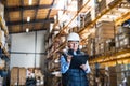 Senior woman warehouse manager or supervisor with white helmet and clipboard. Royalty Free Stock Photo