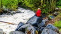 Senior woman watching the turbulent waters of Mcgillivray Creek between the towns of Whitecroft and Sun Peaks