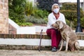 Senior woman wearing a home made face mask and enjoying some time outdoors with her pet during the coronavirus quarantine de-