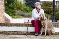 Senior woman wearing a home made face mask and enjoying some time outdoors with her pet during the coronavirus quarantine de-