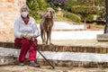 Senior woman wearing a home made face mask and enjoying some time outdoors with her pet during the coronavirus quarantine de-