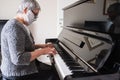 A senior woman wearing a protective face mask while playing the piano at home Royalty Free Stock Photo