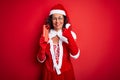 Senior woman wearing Santa Claus costume holding christmas gift over isolated red background happy with big smile doing ok sign, Royalty Free Stock Photo