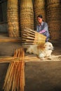 Senior woman weaving basket by hand with a dog lying down