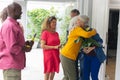 Senior woman welcoming multiracial friends at entrance during house party Royalty Free Stock Photo