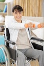 senior woman in wheelchair exercising with dumbbells at home