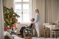 A senior woman in wheelchair with a health visitor at home at Christmas time. Royalty Free Stock Photo