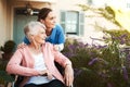 Senior woman, wheelchair and nurse in elderly care, support or garden walk at nursing home. Happy mature female and Royalty Free Stock Photo