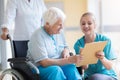 Senior woman in wheelchair with nurse in hospital