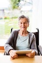 Senior woman in a wheelchair with tablet at home. Royalty Free Stock Photo