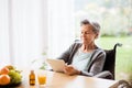 Senior woman in a wheelchair with tablet at home. Royalty Free Stock Photo