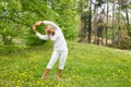 Senior woman in white stretching arms.