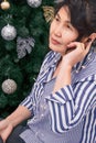Senior woman with wireless headphones listen music or podcast on phone in home bedroom at Christmas, wireless technology