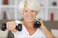 senior woman working out with dumbbells in home