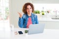 Senior woman working using computer laptop pointing and showing with thumb up to the side with happy face smiling Royalty Free Stock Photo