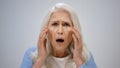 Senior woman worrying about health inside. Shocked lady opening mouth indoor. Royalty Free Stock Photo