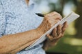 Senior woman writing down her memories into a notebook