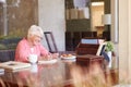Senior Woman Writing Memoirs In Book At Desk Royalty Free Stock Photo