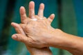 Senior woman& x27;s hands washing her hands using soap foam in step 2 on bokeh blue swimming pool, Prevention from covid19