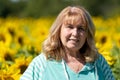 Senior woman 60-65 years poses in front of a field of sunflowers Royalty Free Stock Photo