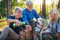 Senior women friends with dog on walk outdoors in forest. Royalty Free Stock Photo