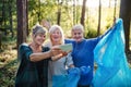 Senior women friends picking up litter outdoors in forest, taking selfie. Royalty Free Stock Photo