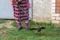 A senior women with a gas mower in her hands, mowing grass in front of the house Royalty Free Stock Photo