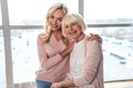 Senior woman and her attractive daughter spending time together at home and sitting on sofa. Happy Mothers` Day Royalty Free Stock Photo