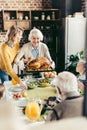 senior woman and her daughter carrying turkey for thanksgiving dinner with their Royalty Free Stock Photo