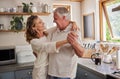 Senior woman and man dancing in their kitchen, enjoying their retirement. Love, family and happiness for elderly Royalty Free Stock Photo