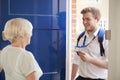 Senior woman opens door to male care worker showing his ID Royalty Free Stock Photo