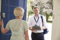 Senior woman opens door to male charity worker doing survey