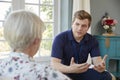 Senior woman talking with male care worker on home visit Royalty Free Stock Photo