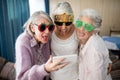 Senior women wearing novelty glasses making face while taking selfie