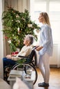 A senior woman in wheelchair with a health visitor at home at Christmas time. Royalty Free Stock Photo