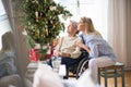 A senior woman in wheelchair with a health visitor at home at Christmas time. Royalty Free Stock Photo