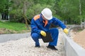 Senior worker checks the correctness of the construction of the road using a measuring tape