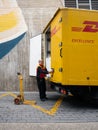 Senior worker discharge DHL parcels from truck in central square