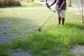 Senior worker mows grass in the yard with electric hand trimmer Royalty Free Stock Photo