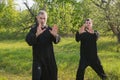 Senior and young guy do Qi Gong or Tai Chi exercise in the apple garden Royalty Free Stock Photo