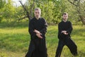 Senior and young guy do Qi Gong or Tai Chi exercise in the apple savage garden Royalty Free Stock Photo