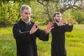 Senior and young guy do Qi Gong or Tai Chi exercise in the park Royalty Free Stock Photo