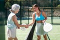 Senior and young women handshaking after padel tennis match