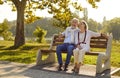 Beautiful stylish elderly couple in love is sitting on bench in city park on warm summer evening. Royalty Free Stock Photo