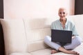 Seniors and Technologies Concepts. Smiling Relaxing Caucasian Senior Woman Posing With Laptop And Listening To The Music on Couch