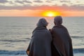 seniors wrapped in blanket, seaside sunrise, back view Royalty Free Stock Photo