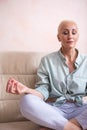 Seniors and Yoga Concepts. Portrait of Relaxing Caucasian Senior Woman Posing in Yoga Asana Pose on Couch With Closed Eyes Indoors