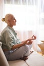 Seniors and Yoga Concepts. Profile Portrait of Relaxing Caucasian Senior Woman Posing in Yoga Asana Pose on Couch With Closed Eyes