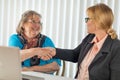 Senior Woman Shaking Hands with Businesswoman Near Laptop Computer